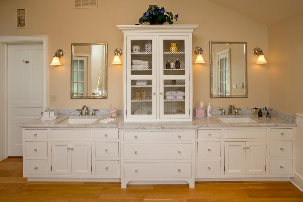 Badezimmer En Suite mit weißen Schränken, gelber Wandfarbe, hellem Holzboden und Marmor-Waschbecken/Waschtisch in Philadelphia