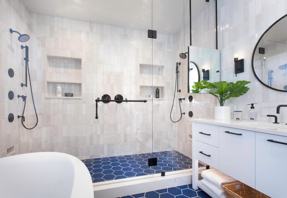 Источник вдохновения для домашнего уюта: большая главная ванная комната в морском стиле с плоскими фасадами, белыми фасадами, отдельно стоящей ванной, двойным душем, унитазом-моноблоком, белой плиткой, керамической плиткой, белыми стенами, полом из керамогранита, врезной раковиной, столешницей из искусственного кварца, синим полом, душем с распашными дверями, белой столешницей, нишей, тумбой под две раковины и встроенной тумбой