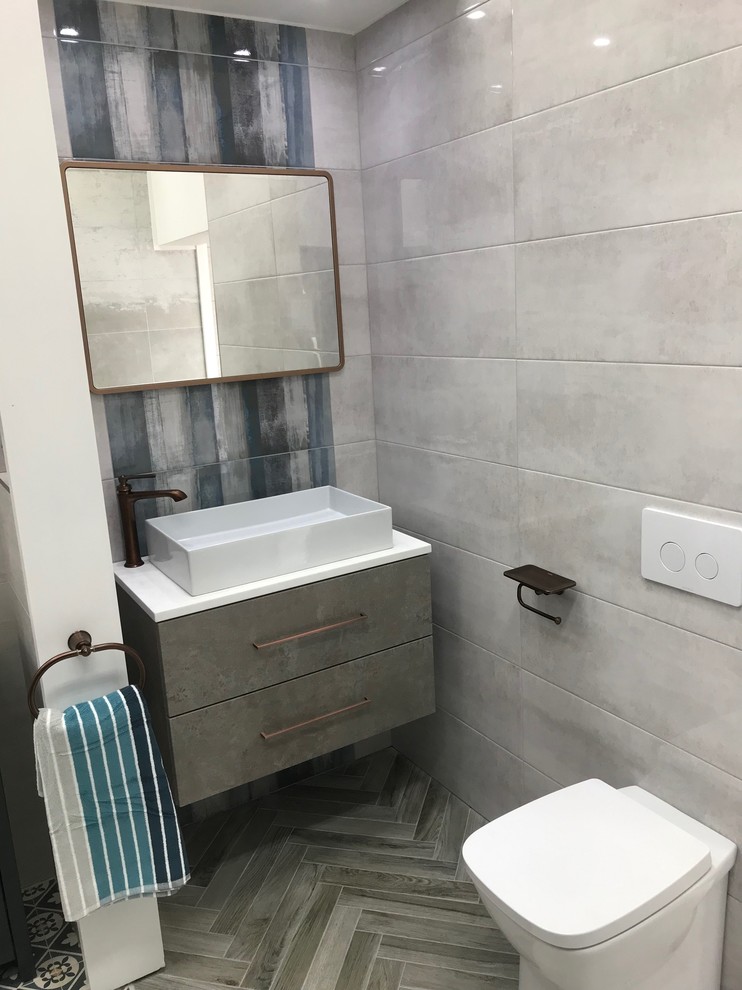 Cette image montre une salle de bain principale minimaliste avec WC à poser, un carrelage gris, des carreaux de céramique, un mur gris, un sol en carrelage de porcelaine, un lavabo suspendu, un plan de toilette en surface solide, un sol gris et un plan de toilette blanc.