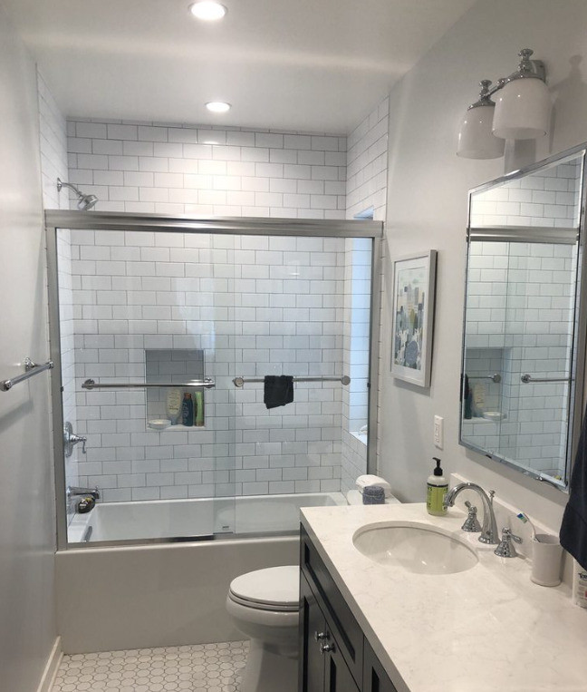 Modern inredning av ett mellanstort badrum, med en dusch/badkar-kombination, vit kakel, keramikplattor, vita väggar, vitt golv och dusch med skjutdörr