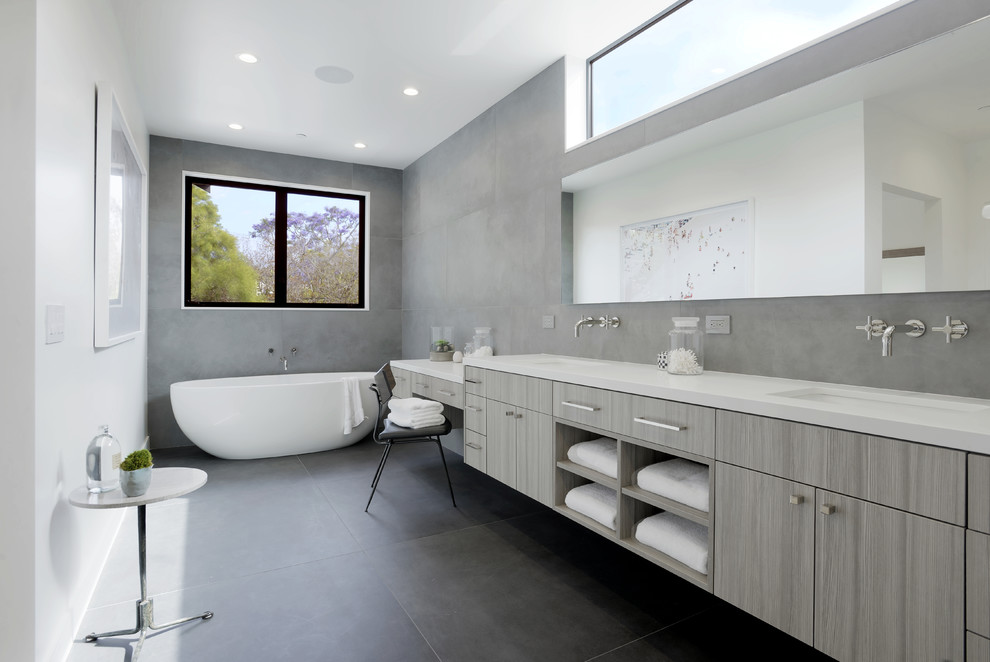 Inspiration pour une salle de bain principale design avec un placard à porte plane, des portes de placard grises, un mur gris, un sol en ardoise, un lavabo encastré, un sol gris, un carrelage gris et une baignoire indépendante.