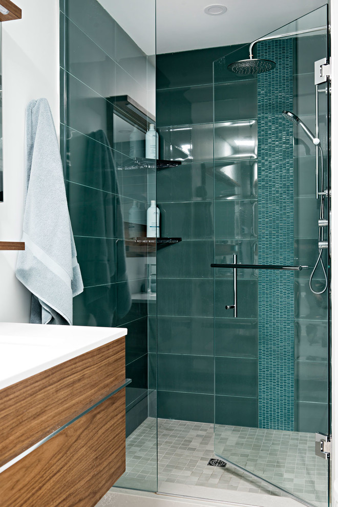 Inspiration for a mid-sized modern master blue tile and glass tile ceramic tile and gray floor bathroom remodel in Toronto with flat-panel cabinets, medium tone wood cabinets, a wall-mount toilet, gray walls, an integrated sink, a hinged shower door and white countertops