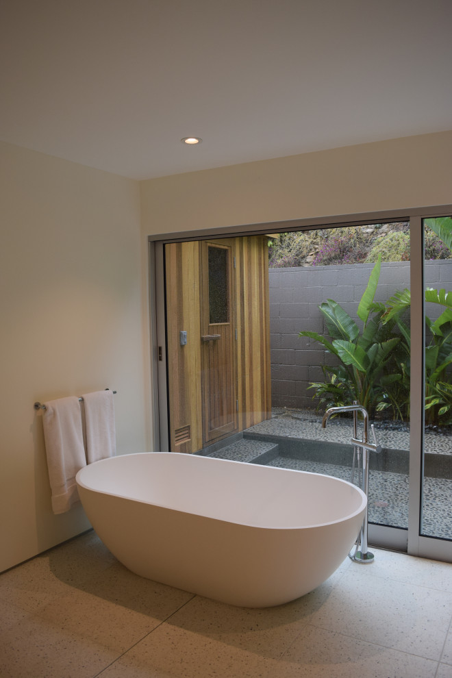 This is an example of a modern bathroom in Los Angeles with flat-panel cabinets, a submerged sink, engineered stone worktops, white worktops, a built in vanity unit, a freestanding bath and terrazzo flooring.