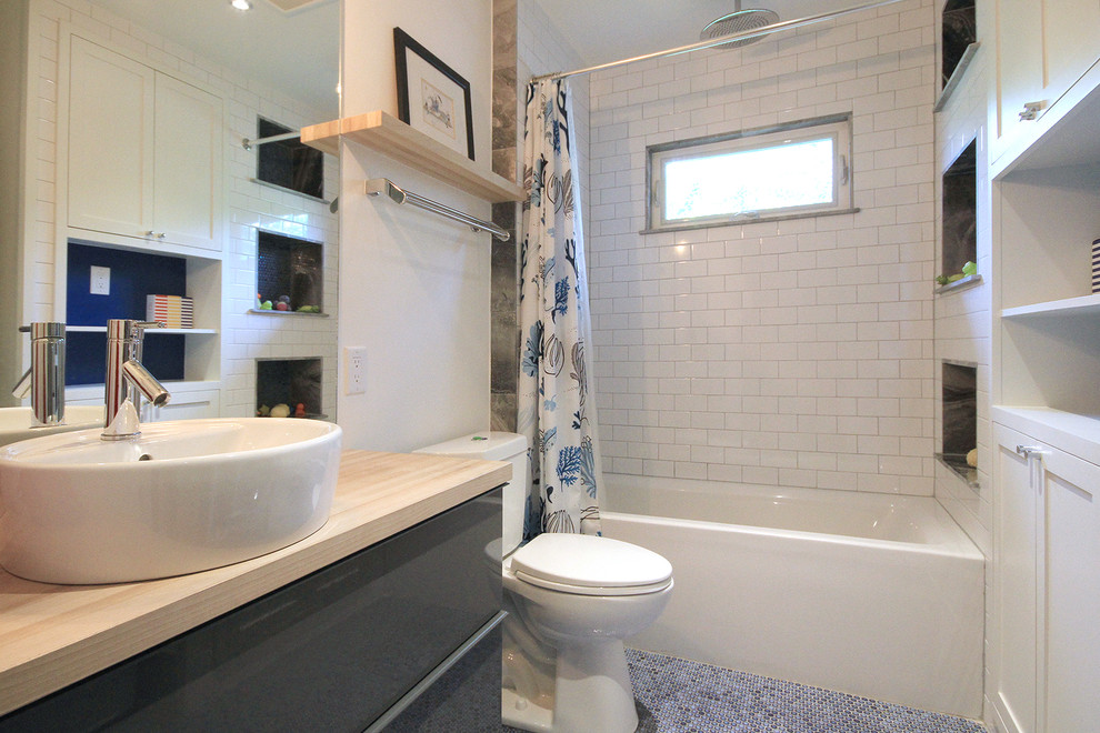 Cette image montre une salle de bain traditionnelle de taille moyenne pour enfant avec un placard à porte shaker, des portes de placard blanches, une baignoire en alcôve, WC séparés, un carrelage blanc, un carrelage métro, un mur blanc, un sol en carrelage de terre cuite, une vasque, un plan de toilette en bois, un combiné douche/baignoire, un sol bleu et une cabine de douche avec un rideau.