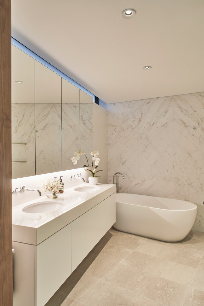 Inredning av ett modernt mellanstort beige beige en-suite badrum, med släta luckor, vita skåp, ett fristående badkar, beige kakel, grå kakel, ett undermonterad handfat och beiget golv