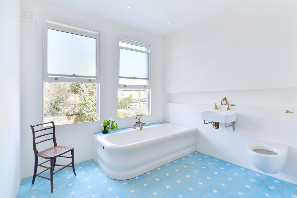 Corner bathtub - mid-sized contemporary 3/4 cement tile floor and blue floor corner bathtub idea in London with a wall-mount toilet, white walls and a wall-mount sink