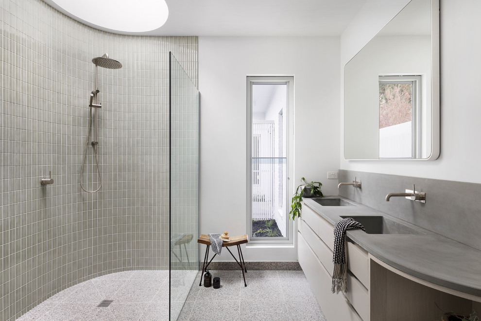 Inredning av ett modernt stort grå grått en-suite badrum, med en kantlös dusch, terrazzogolv, bänkskiva i betong, med dusch som är öppen, släta luckor, beige skåp, grå kakel, mosaik, vita väggar, ett integrerad handfat och grått golv