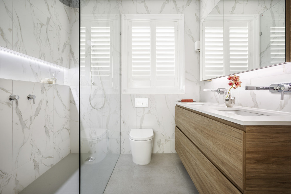 Bild på ett litet funkis vit vitt badrum, med skåp i mellenmörkt trä, en dubbeldusch, en vägghängd toalettstol, klinkergolv i porslin, ett undermonterad handfat, bänkskiva i kvarts, grått golv och med dusch som är öppen