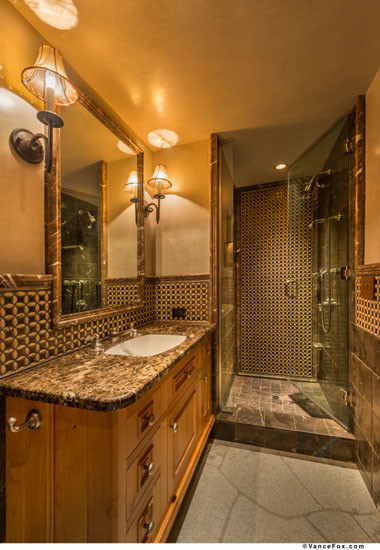 Exemple d'une douche en alcôve montagne en bois brun de taille moyenne avec un lavabo posé, un placard avec porte à panneau surélevé, un plan de toilette en surface solide, une baignoire posée, un carrelage multicolore, un carrelage de pierre et un mur multicolore.