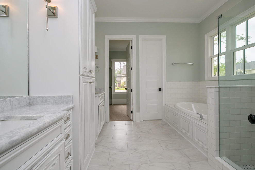 На фото: главная ванная комната в стиле неоклассика (современная классика) с белыми фасадами, ванной в нише, угловым душем, белой плиткой, керамогранитной плиткой, зелеными стенами, врезной раковиной, столешницей из гранита, мраморным полом, серым полом и душем с распашными дверями