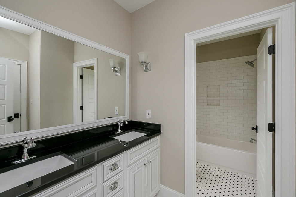 Design ideas for a classic bathroom in Atlanta with raised-panel cabinets, white cabinets, a built-in bath, a shower/bath combination, a one-piece toilet, black and white tiles, ceramic tiles, beige walls, ceramic flooring, a submerged sink and granite worktops.