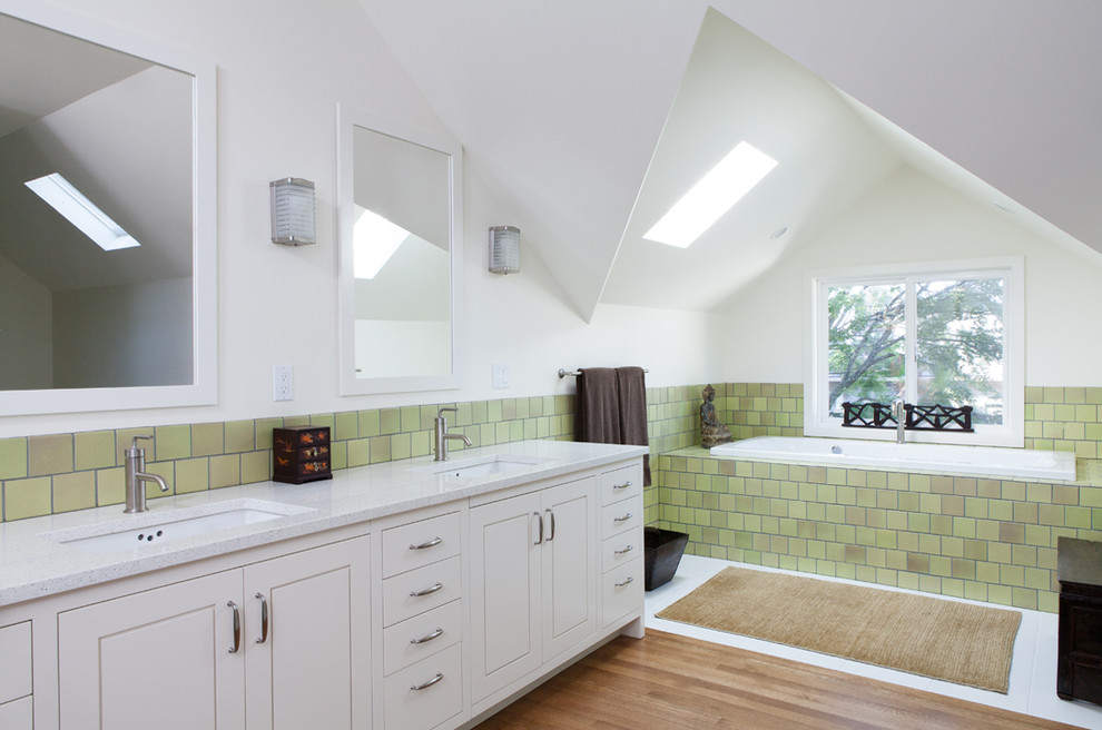 Idéer för funkis badrum, med ett undermonterad handfat, vita skåp, bänkskiva i återvunnet glas, ett badkar i en alkov, grön kakel, tunnelbanekakel, vita väggar och ljust trägolv