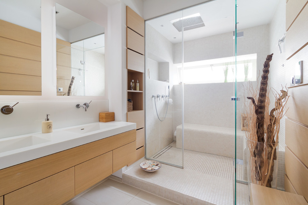 Réalisation d'une salle de bain design en bois brun avec un placard à porte plane, un carrelage beige, mosaïque, un mur blanc, un lavabo intégré et une cabine de douche à porte battante.