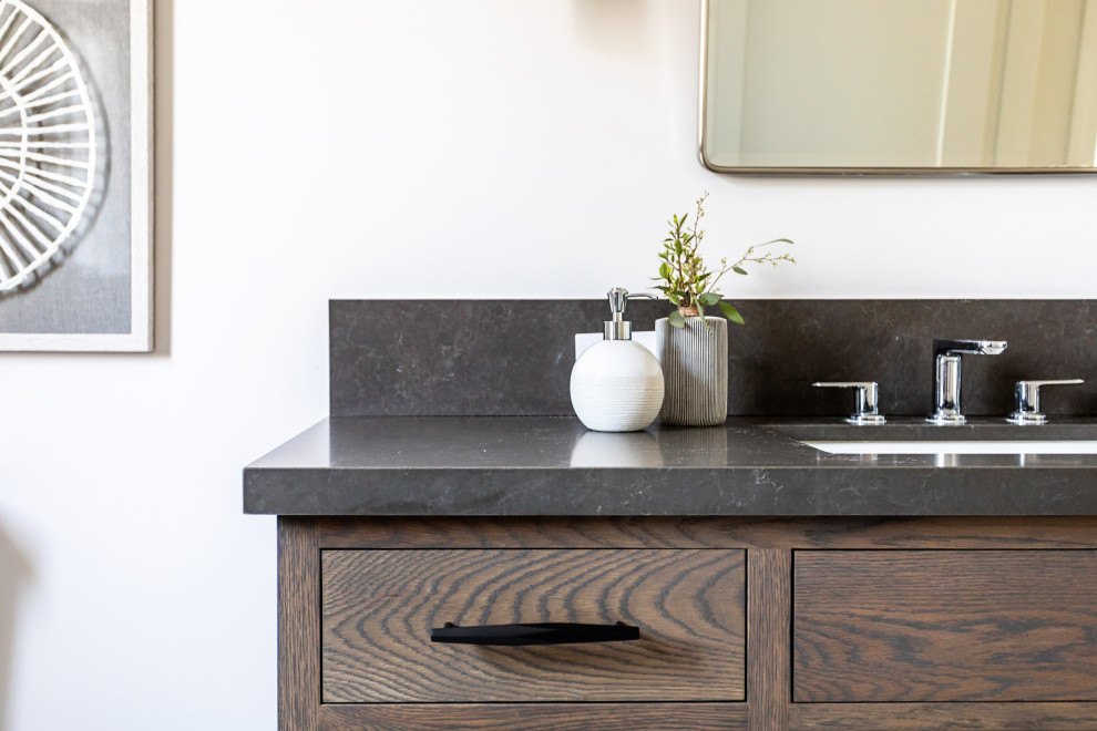 Mid-sized country master marble floor and white floor bathroom photo in Los Angeles with recessed-panel cabinets, dark wood cabinets, a one-piece toilet, beige walls, an undermount sink, granite countertops and black countertops