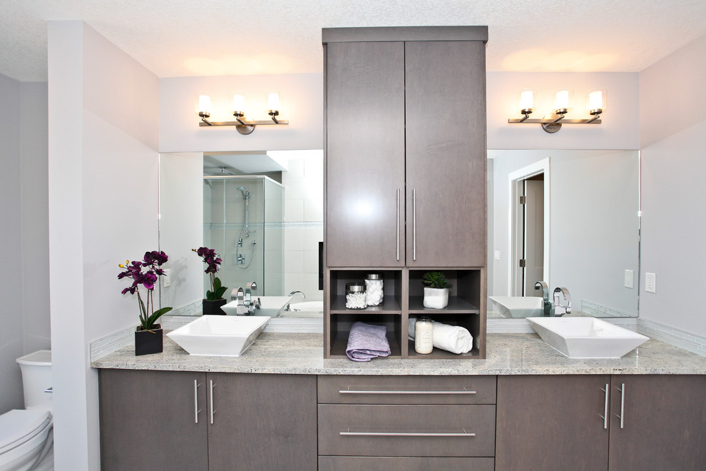 Photo of a medium sized contemporary ensuite bathroom in Calgary with flat-panel cabinets, grey cabinets, a built-in bath, a corner shower, a two-piece toilet, beige tiles, porcelain tiles, grey walls, porcelain flooring, a vessel sink and granite worktops.