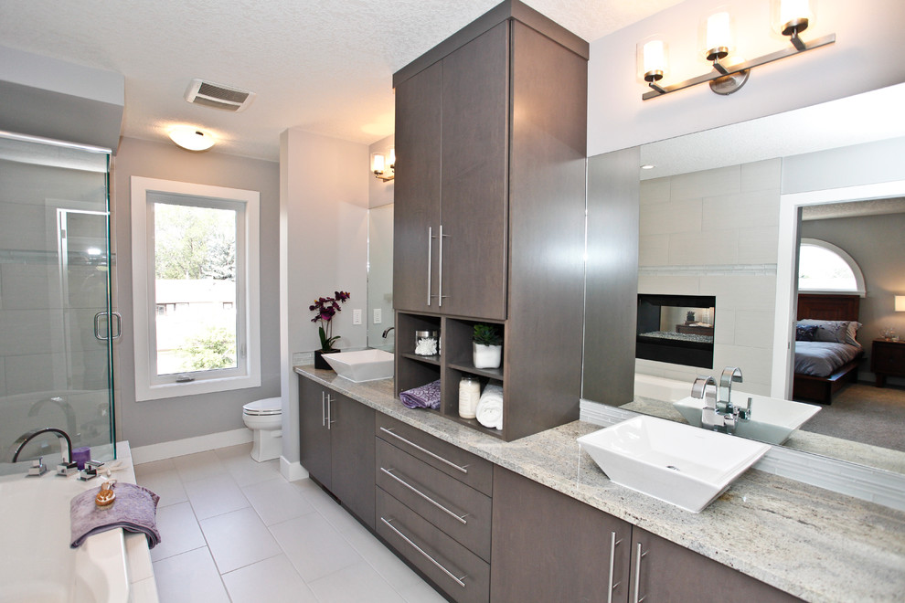 This is an example of a medium sized contemporary ensuite bathroom in Calgary with flat-panel cabinets, grey cabinets, a built-in bath, a corner shower, beige tiles, porcelain tiles, grey walls, porcelain flooring, a vessel sink and granite worktops.