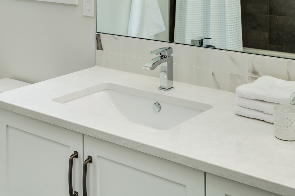 Inredning av ett lantligt mellanstort badrum med dusch, med skåp i shakerstil, vita skåp, en toalettstol med separat cisternkåpa, vita väggar, betonggolv, ett undermonterad handfat, bänkskiva i kvartsit och grått golv