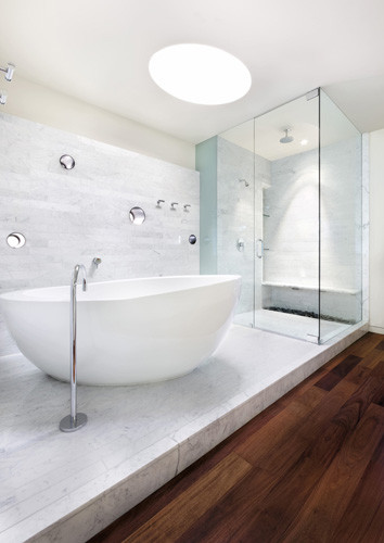 Idee per una stanza da bagno padronale minimalista con ante lisce, vasca freestanding, doccia aperta, piastrelle bianche, piastrelle in pietra, pareti bianche e pavimento in legno massello medio