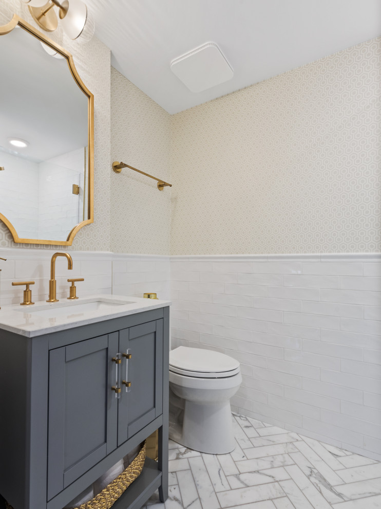 На фото: маленькая ванная комната в стиле неоклассика (современная классика) с фасадами в стиле шейкер, серыми фасадами, душем в нише, раздельным унитазом, белой плиткой, плиткой кабанчик, бежевыми стенами, мраморным полом, душевой кабиной, врезной раковиной, столешницей из искусственного кварца, белым полом, душем с распашными дверями, белой столешницей, тумбой под одну раковину, напольной тумбой и обоями на стенах для на участке и в саду