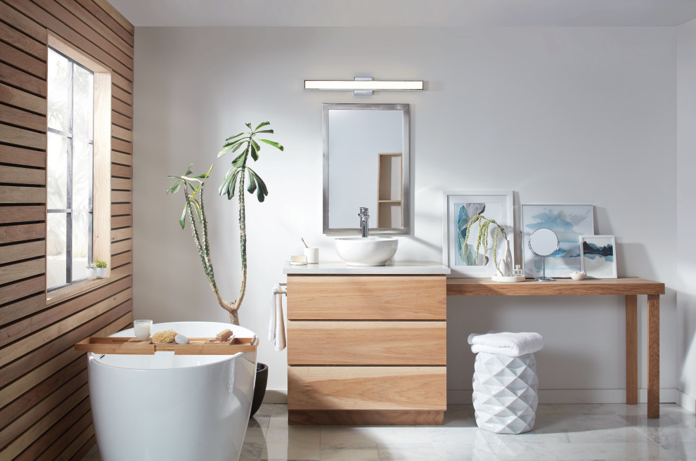 Photo of a medium sized contemporary ensuite bathroom in Other with white tiles, white walls, a vessel sink, a built in vanity unit, light wood cabinets, a freestanding bath, ceramic flooring, solid surface worktops, white floors, grey worktops, a single sink and panelled walls.