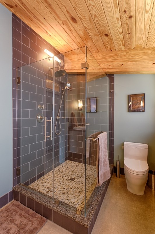 Cette photo montre une salle de bain principale moderne de taille moyenne avec un placard à porte plane, des portes de placard blanches, une douche d'angle, WC à poser, un carrelage gris, un carrelage métro, un mur bleu, sol en béton ciré, un lavabo posé et un plan de toilette en quartz modifié.