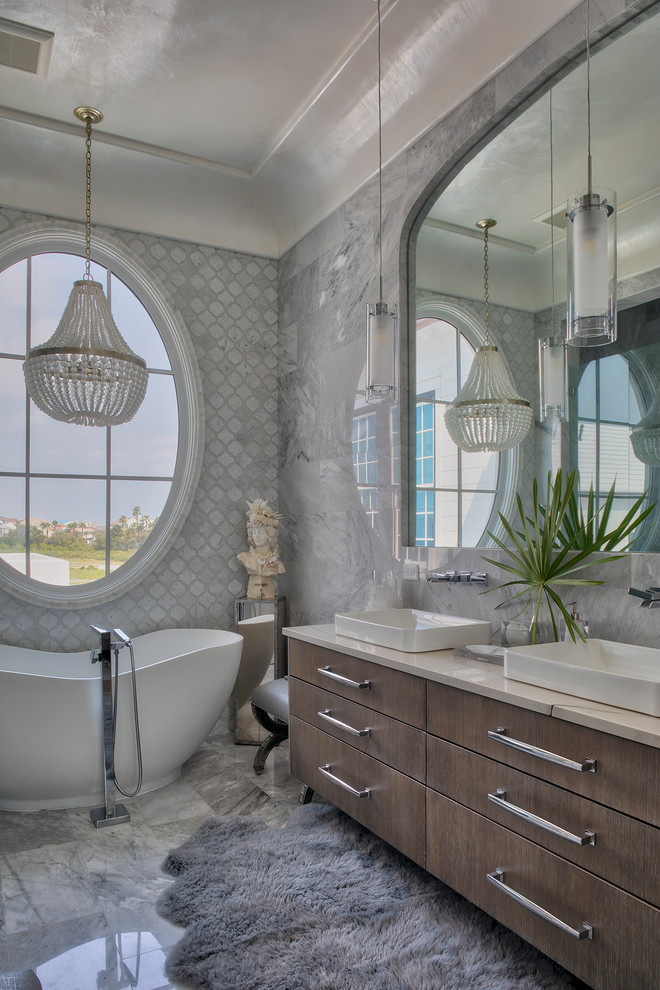 На фото: главная ванная комната в морском стиле с плоскими фасадами, темными деревянными фасадами, отдельно стоящей ванной, серой плиткой, серыми стенами, накладной раковиной, серым полом и бежевой столешницей