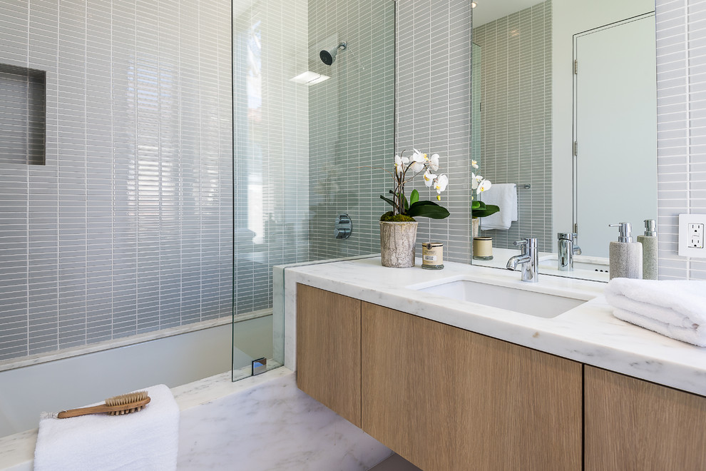 Doorless shower - mid-sized modern gray tile and ceramic tile ceramic tile doorless shower idea in Los Angeles with flat-panel cabinets, medium tone wood cabinets, an undermount tub, a one-piece toilet, white walls, an undermount sink and marble countertops