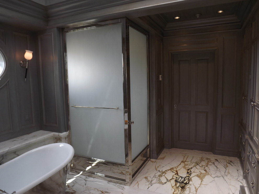 Diseño de cuarto de baño principal tradicional grande con armarios con paneles empotrados, puertas de armario grises, bañera exenta, ducha esquinera, paredes grises, suelo de baldosas de porcelana y encimera de ónix