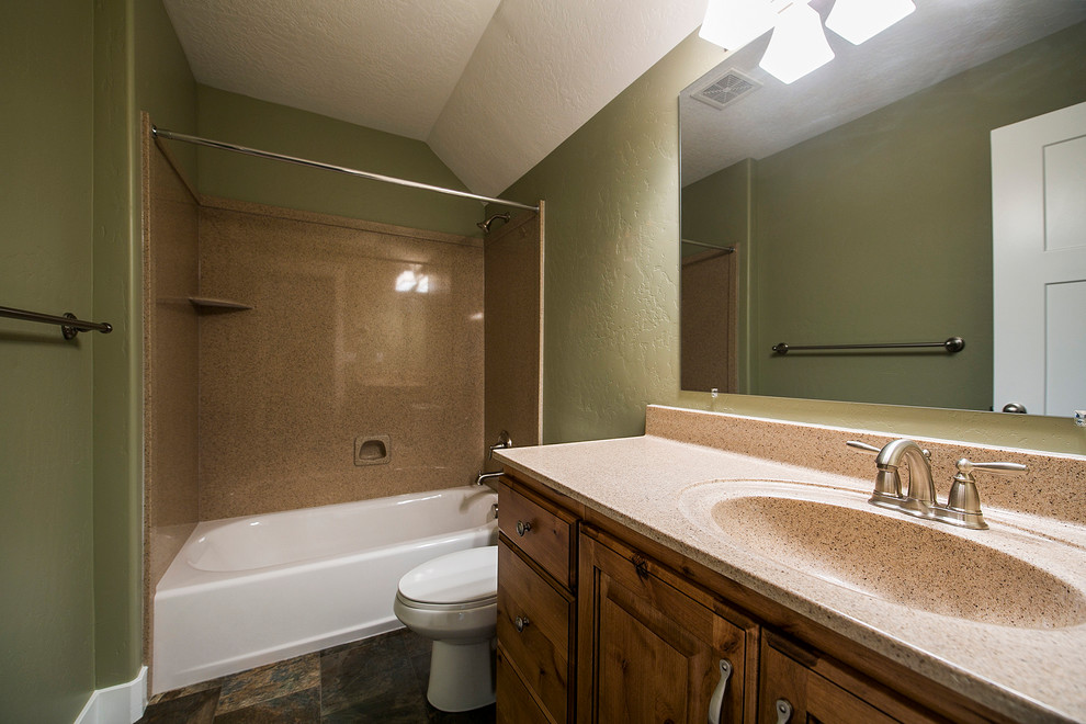 Inredning av ett amerikanskt mellanstort badrum, med luckor med upphöjd panel, skåp i mellenmörkt trä, laminatbänkskiva, gröna väggar och klinkergolv i keramik