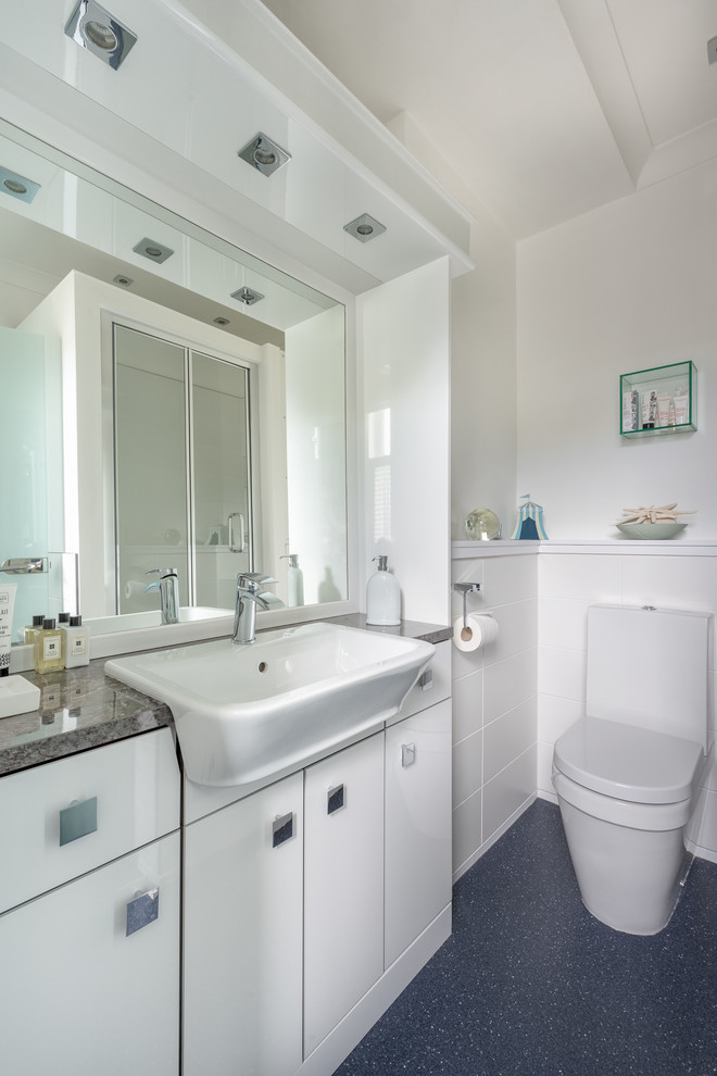 Small contemporary shower room bathroom in Devon with flat-panel cabinets, white cabinets, a corner shower, a two-piece toilet, ceramic tiles, white walls, vinyl flooring and a wall-mounted sink.