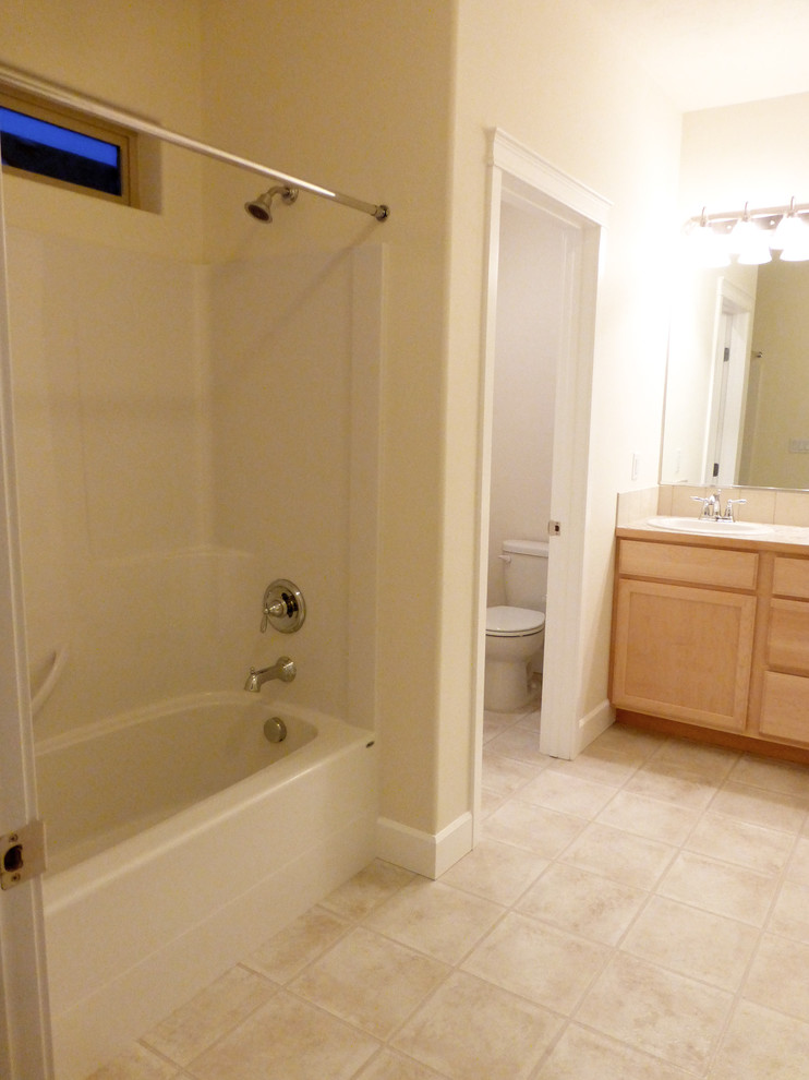 シアトルにあるトラディショナルスタイルのおしゃれなマスターバスルーム (落し込みパネル扉のキャビネット、淡色木目調キャビネット、ラミネートカウンター、シャワー付き浴槽	、リノリウムの床) の写真