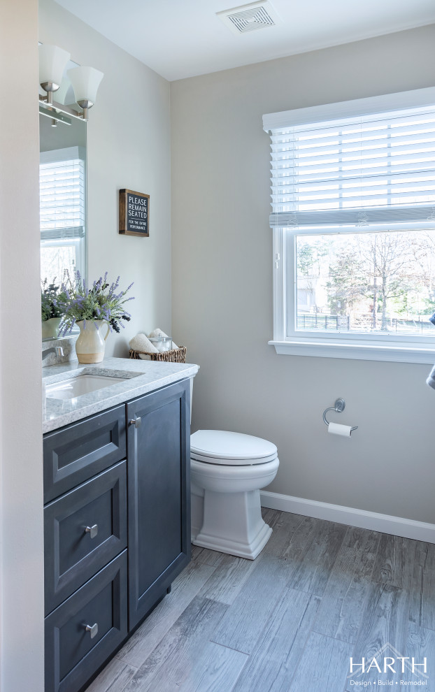 Mid-sized transitional 3/4 white tile and subway tile gray floor and wood-look tile floor bathroom photo in Philadelphia with shaker cabinets, gray cabinets, a two-piece toilet, gray walls, an undermount sink, quartz countertops and gray countertops