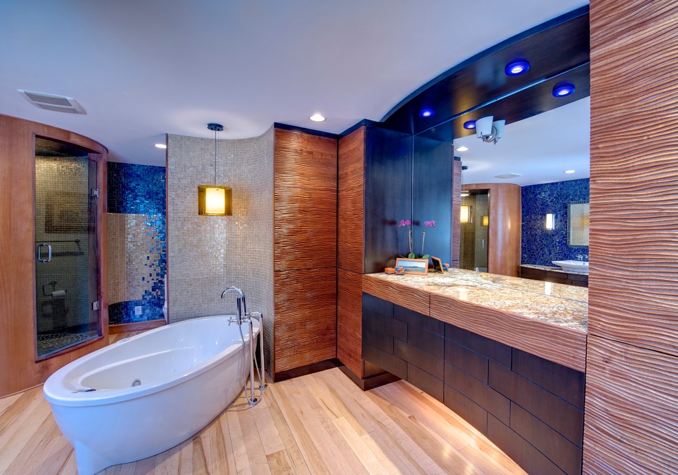 Foto på ett stort funkis en-suite badrum, med en hörndusch, ljust trägolv, dusch med gångjärnsdörr, ett fristående handfat, blå kakel, mosaik, ett fristående badkar, granitbänkskiva, släta luckor och skåp i mörkt trä