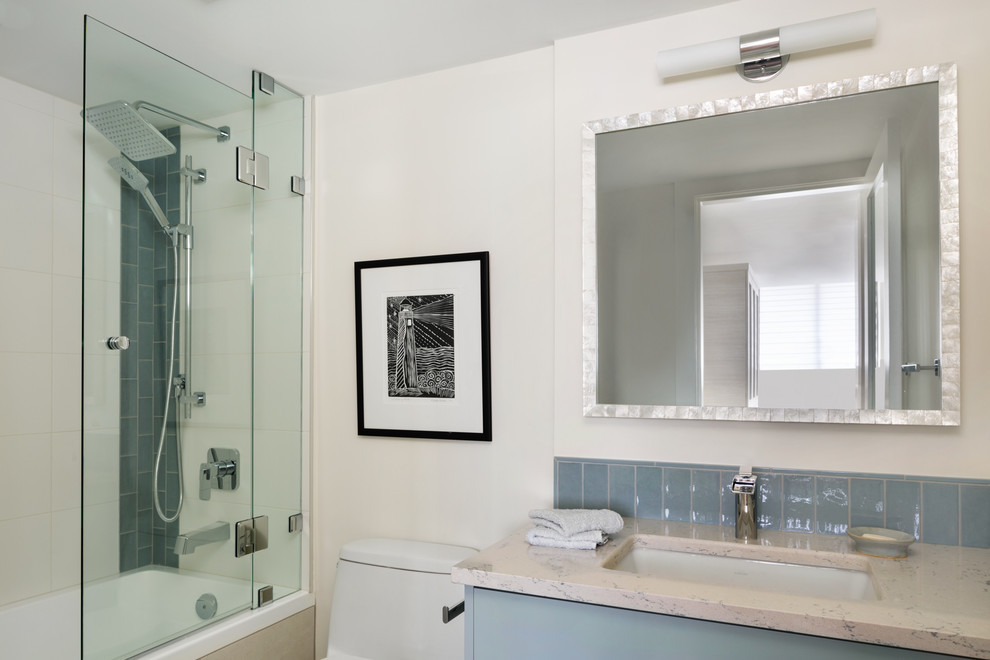 Пример оригинального дизайна: ванная комната среднего размера в стиле фьюжн с плоскими фасадами, серыми фасадами, ванной в нише, душем над ванной, унитазом-моноблоком, серой плиткой, керамической плиткой, полом из керамогранита, врезной раковиной, столешницей из искусственного кварца и душем с распашными дверями