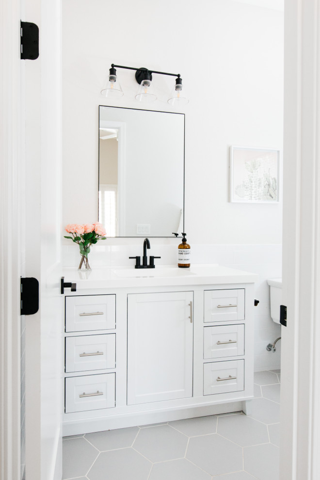 Diseño de cuarto de baño tradicional renovado con armarios estilo shaker, puertas de armario blancas, baldosas y/o azulejos blancos, paredes blancas, lavabo bajoencimera, suelo gris y encimeras blancas