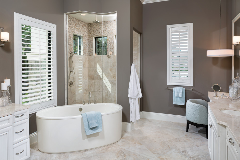 Design ideas for a large traditional ensuite bathroom in Tampa with a submerged sink, recessed-panel cabinets, white cabinets, marble worktops, a freestanding bath, a corner shower, a one-piece toilet, beige tiles, ceramic tiles, grey walls and ceramic flooring.