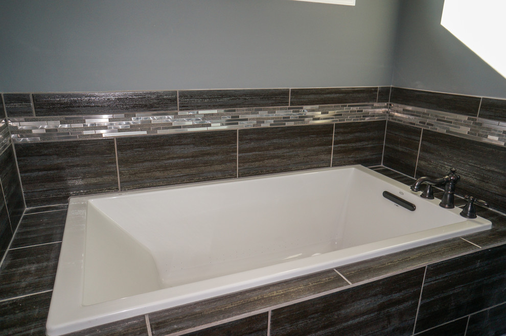 Retro inredning av ett en-suite badrum, med skåp i mörkt trä, grå kakel, grå väggar, ett undermonterad handfat och granitbänkskiva