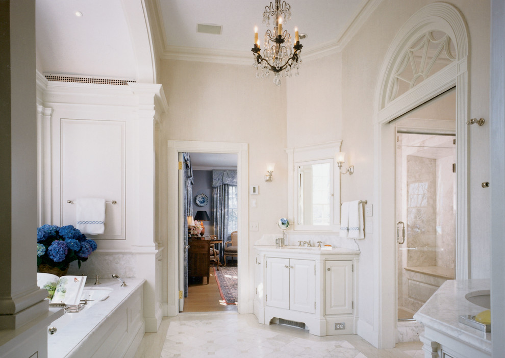 ニューヨークにあるトラディショナルスタイルのおしゃれなマスターバスルーム (落し込みパネル扉のキャビネット、白いキャビネット、大理石の洗面台、アルコーブ型シャワー、白いタイル、大理石の床) の写真