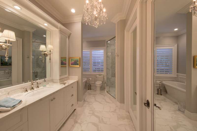 マイアミにある広いトラディショナルスタイルのおしゃれな浴室 (置き型浴槽、アルコーブ型シャワー、白いタイル、グレーの壁、一体型トイレ	) の写真