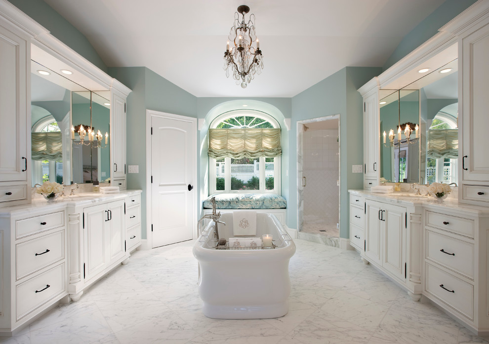 Diseño de cuarto de baño tradicional con lavabo bajoencimera, puertas de armario blancas, bañera exenta, ducha empotrada, baldosas y/o azulejos blancos y armarios con paneles empotrados