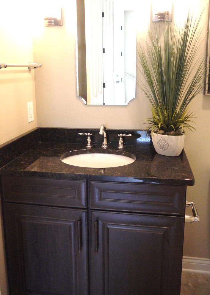 This is an example of a small traditional shower room bathroom in Grand Rapids with raised-panel cabinets, dark wood cabinets, granite worktops, an alcove bath, a shower/bath combination, a one-piece toilet, beige walls and a submerged sink.