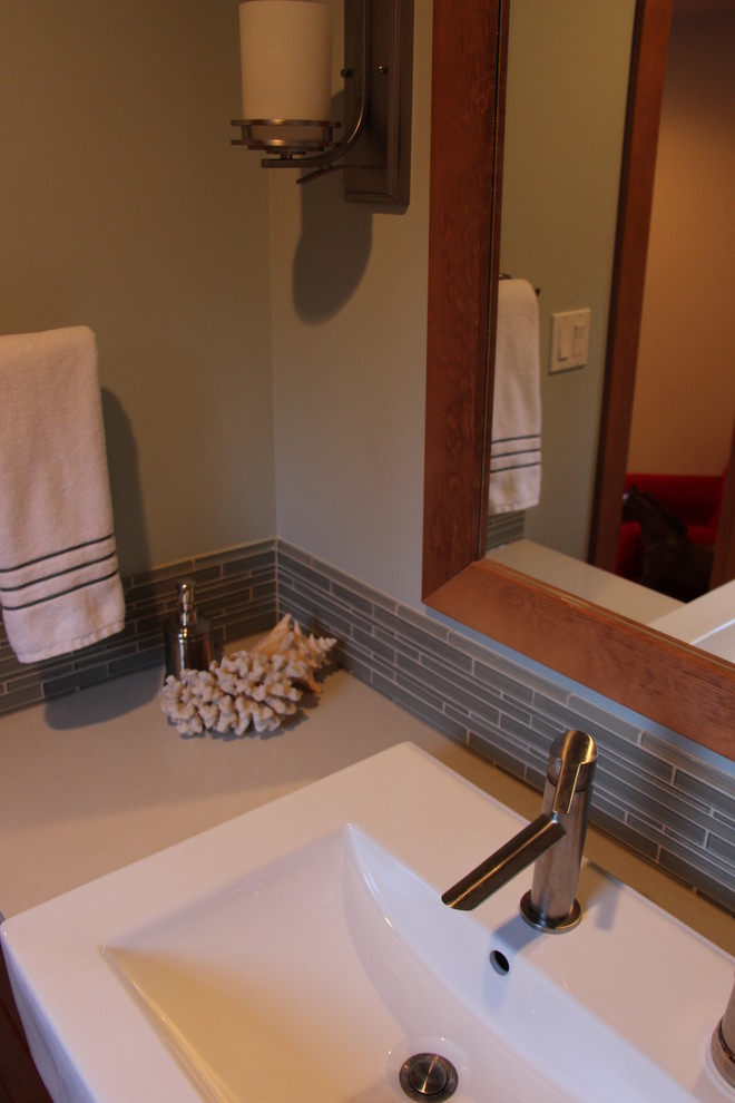 Bild på ett stort vintage badrum för barn, med ett fristående handfat, släta luckor, skåp i mellenmörkt trä, bänkskiva i kvarts, ett badkar i en alkov, en dusch/badkar-kombination, en toalettstol med hel cisternkåpa, grå kakel, porslinskakel, blå väggar och klinkergolv i porslin