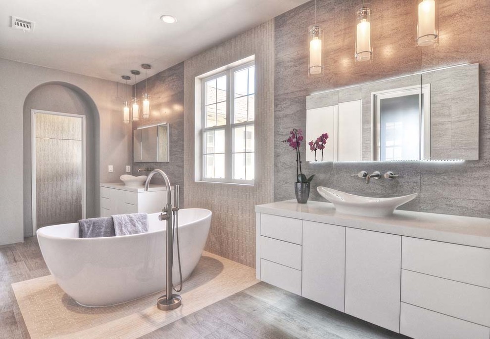 Inspiration for an expansive contemporary ensuite bathroom in Orange County with flat-panel cabinets, white cabinets, a freestanding bath, a walk-in shower, a one-piece toilet, grey tiles, ceramic tiles, grey walls, ceramic flooring, a vessel sink and engineered stone worktops.