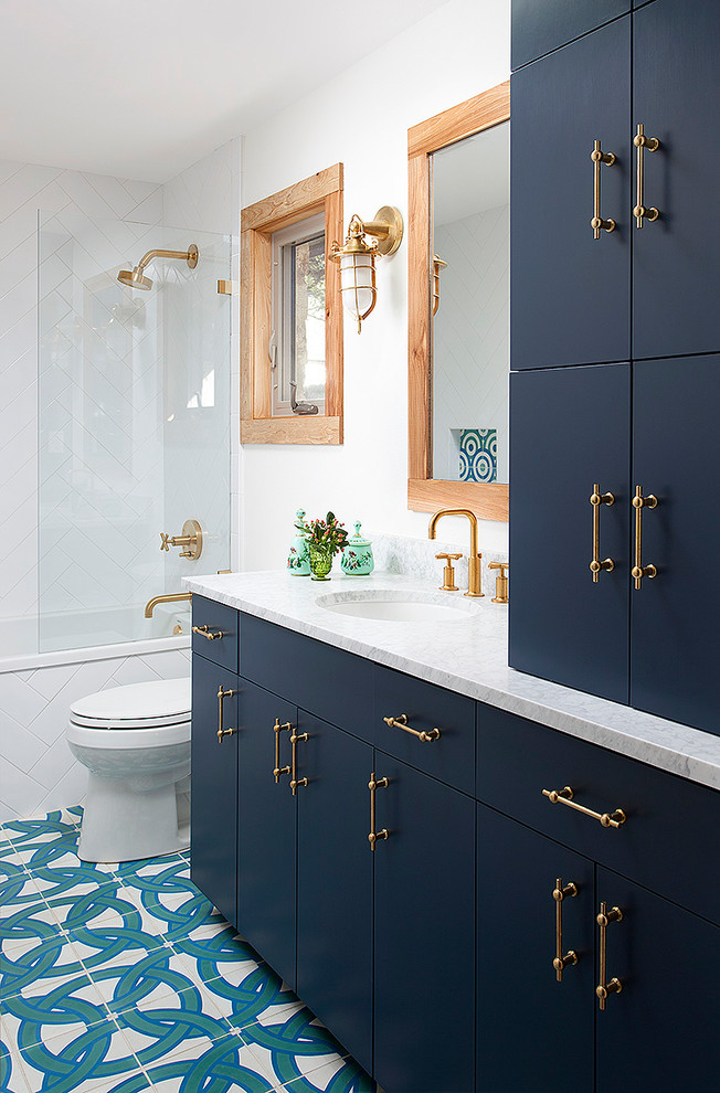 Exemple d'une salle de bain chic avec un placard à porte plane, des portes de placard bleues, une baignoire en alcôve, un combiné douche/baignoire, un carrelage bleu, un carrelage multicolore, un carrelage blanc, un mur blanc, un lavabo encastré et un sol multicolore.