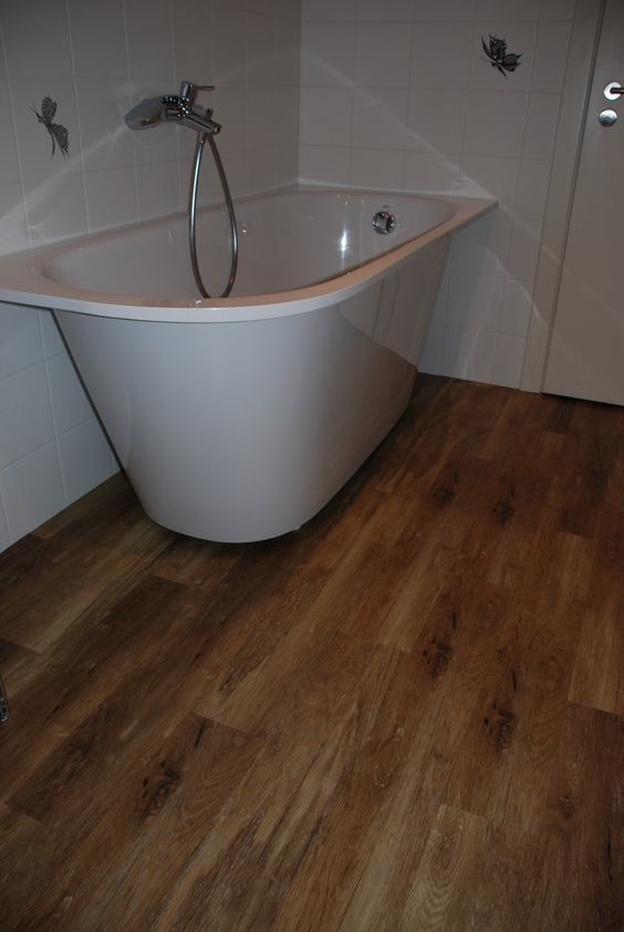 Inspiration pour une salle d'eau traditionnelle de taille moyenne avec une baignoire indépendante, un mur blanc, un sol en bois brun et un sol marron.