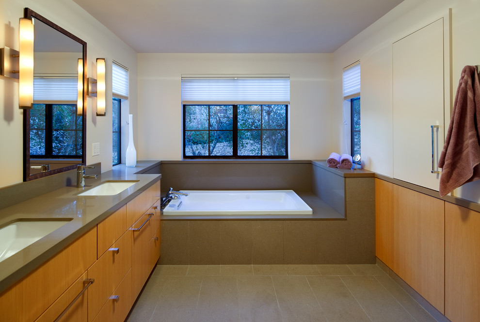 Cette image montre une salle de bain principale minimaliste en bois brun de taille moyenne avec un lavabo encastré, un placard à porte plane, une baignoire posée et un mur blanc.