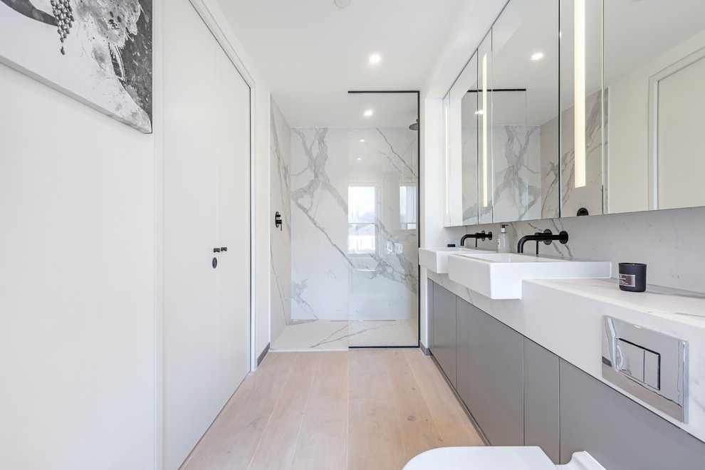 Стильный дизайн: ванная комната в современном стиле с плоскими фасадами, серыми фасадами, душем в нише, инсталляцией, серой плиткой, белой плиткой, плиткой из листового камня, белыми стенами, светлым паркетным полом, душевой кабиной, накладной раковиной, бежевым полом, открытым душем и белой столешницей - последний тренд