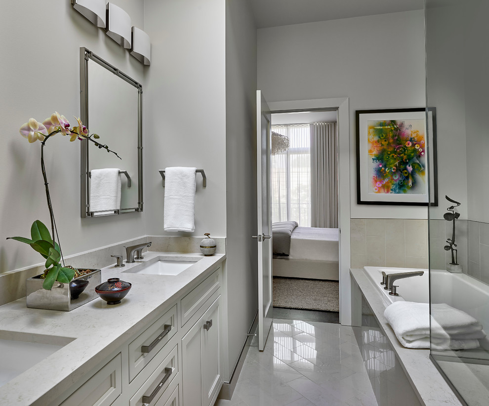 Пример оригинального дизайна: главная ванная комната в современном стиле с фасадами с утопленной филенкой, белыми фасадами, накладной ванной, угловым душем, унитазом-моноблоком, бежевой плиткой, каменной плиткой, серыми стенами, мраморным полом, врезной раковиной и мраморной столешницей