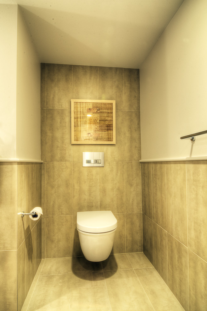 Esempio di un bagno di servizio design di medie dimensioni con lavabo sottopiano, ante lisce, ante in legno chiaro, top in quarzo composito, WC sospeso, piastrelle beige, piastrelle in gres porcellanato, pareti beige e pavimento in travertino