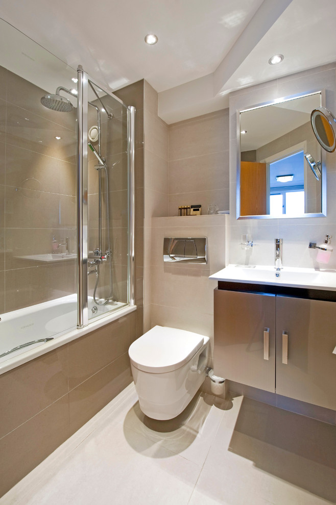Exempel på ett litet modernt en-suite badrum, med släta luckor, bruna skåp, en vägghängd toalettstol, keramikplattor, bänkskiva i akrylsten, ett badkar i en alkov, beige kakel, ett avlångt handfat, en dusch/badkar-kombination, beige väggar, dusch med gångjärnsdörr, klinkergolv i keramik och vitt golv